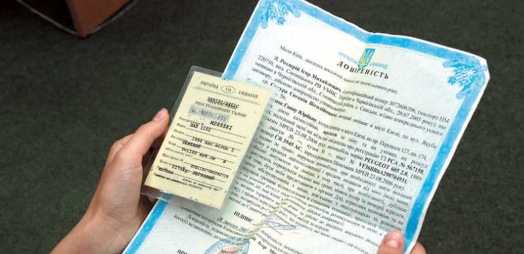 Руки держат украинскую нотариальную доверенность «Довіреність» с гербом Украины и небольшой идентификационной карточкой UA